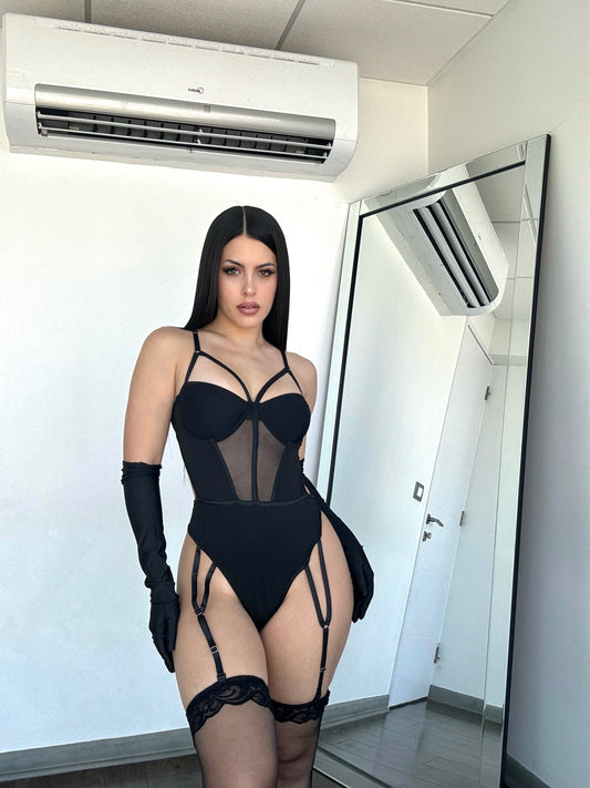 modelo cavrini con body negro con ligas y medias, usa guantes con fondo espejo y aire acondicionado.