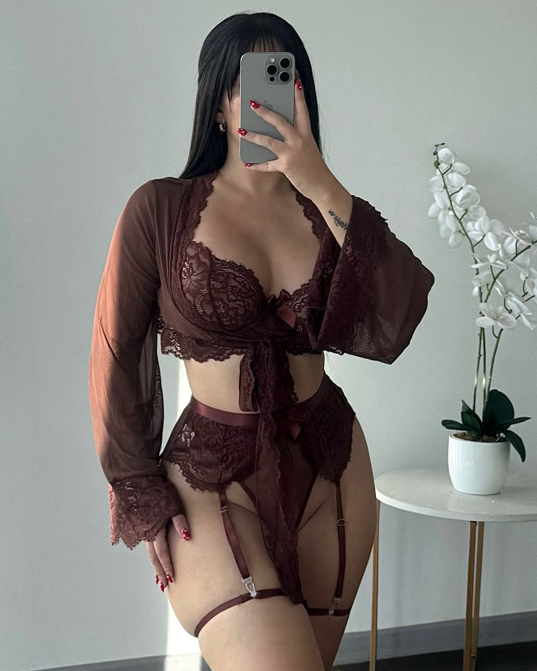 Modelo vistiendo conjunto de lencería de encaje color café con sosten, liguero, panty y bata traslúcida de mangas largas – Cavrini.