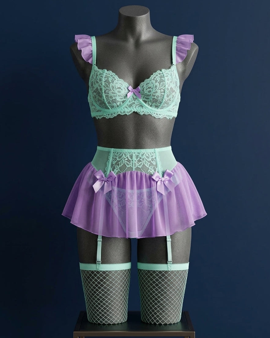 Set de lencería romántica Atlántida en tono verde turquesa y morado sobre maniquí, con bralette de encaje, minifalda de tul, ligueros y medias de red.