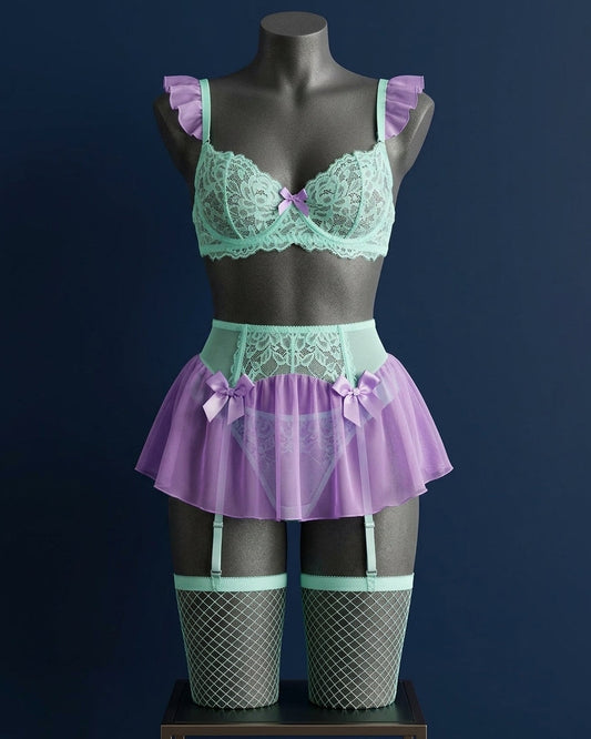 Set de lencería romántica Atlántida en tono verde turquesa y morado sobre maniquí, con bralette de encaje, minifalda de tul, ligueros y medias de red.